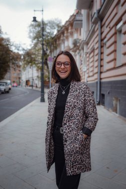 Moskova 'da güzel bir esmer kadın yürüyor. Moda bir leopar ceketiyle. Gülümsüyor ve şehirde yürüyor. Alışverişe.