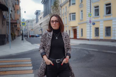 Moskova 'da güzel bir esmer kadın yürüyor. Moda bir leopar ceketiyle. Gülümsüyor ve şehirde yürüyor. Alışverişe.