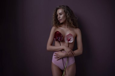 Bir odada kıvırcık saçlı bir kadının nazik portresi. Model sandığı kırmızı ve pembe Callas kaplıyor. Fikir ve kadınlık kavramı, şefkat, bahar ve cinsellik.