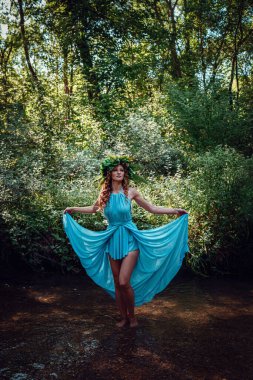 Kızıl saçlı, çiçekli ve eğrelti otlu güzel bir kadın yaz ortasında, Gündönümü Günü 'nü kutluyor..