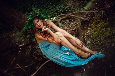 Kızıl saçlı, çiçekli ve eğrelti otlu güzel bir kadın yaz ortasında, Gündönümü Günü 'nü kutluyor..