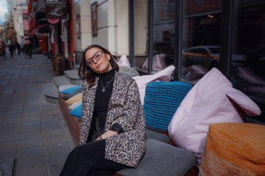 Moskova 'da güzel bir esmer kadın yürüyor. Moda bir leopar ceketiyle. Gülümsüyor ve şehirde yürüyor. Alışverişe.