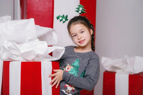stock image Portrait of cheerful elf kid smiling and ready to help in christmas night. wearing fantasy costume isolated over white background with red gift boxes