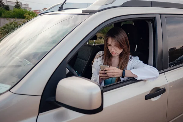 a beautiful young woman driving a grey car. woman using gps on mobile smartphone. the idea and concept of car travel, navigation and freedom