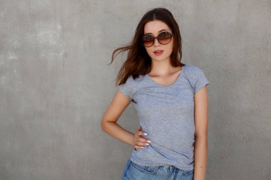 Fotokopi alanı olan güzel bir kadın model. Beyaz gri tişört ve kot pantolon giyen hippi Asyalı kız sokak duvarına karşı poz veriyor, minimalist kentsel giyim tarzı, tişört baskı mağazası modeli