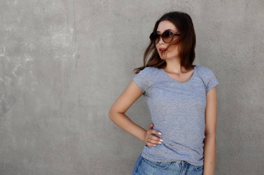 Fotokopi alanı olan güzel bir kadın model. Beyaz gri tişört ve kot pantolon giyen hippi Asyalı kız sokak duvarına karşı poz veriyor, minimalist kentsel giyim tarzı, tişört baskı mağazası modeli