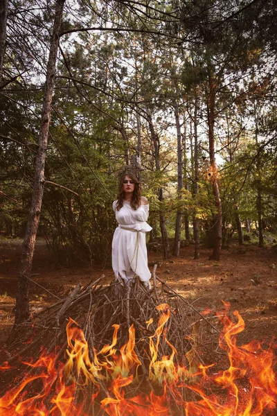 秋の森の中で長い白いドレスを着た美しい謎のゴシック女性 闇のファンタジークリエイター魔女のためのたき火 — ストック写真