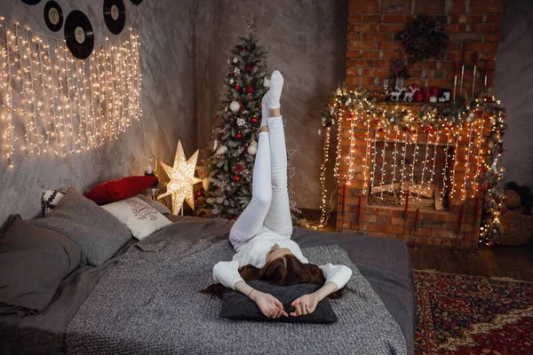 아름다운 스웨터를 새해를 침대에 모조같은 여자가 다락방에 크리스마스 트리에 기대어 — 스톡 사진