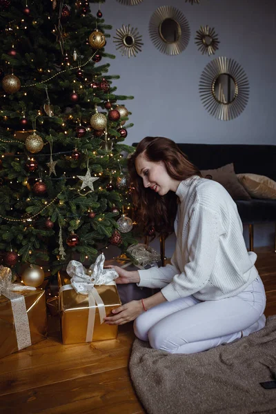 クリスマスの幸せな美しい女性 プレゼント付きのクリスマスツリーの近くの美容女性 新年のコンセプト 快適なホームコンセプト 柔らかい繊維の概念 — ストック写真