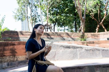 Koyu mavi elbiseli uzun saçlı kadın mesajı akıllı telefondan aldıktan sonra cevabı düşünüyor..