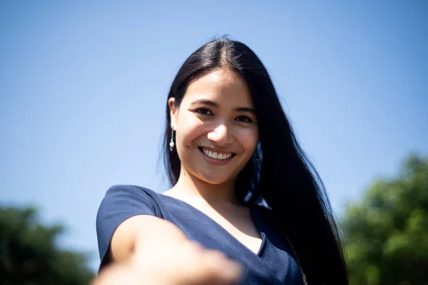 Low angle shot of long hair woman standing in sunlight in windy day and hold her boyfriend\'s hand in the park with blue sky.