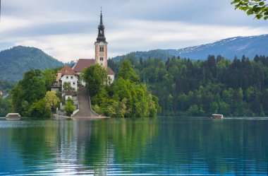 Bled Gölü 'nde güzel bir sabah ve arka planda Julian Alps. Göl adası ve Mary 'nin Varsayımına adanmış küçük sevimli kilise Slovenya' daki ünlü turistik merkezlerdir.