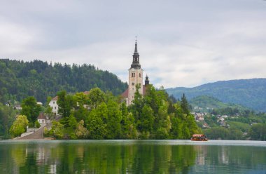 Bled Gölü 'nde güzel bir sabah ve arka planda Julian Alps. Göl adası ve Mary 'nin Varsayımına adanmış küçük sevimli kilise Slovenya' daki ünlü turistik merkezlerdir.
