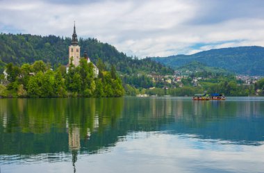 Bled Gölü 'nde güzel bir sabah ve arka planda Julian Alps. Göl adası ve Mary 'nin Varsayımına adanmış küçük sevimli kilise Slovenya' daki ünlü turistik merkezlerdir.