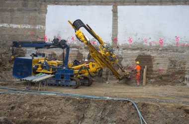Graz / Avusturya - 09 Ekim 2019: inşaat alanında çalışan işçiler ve yerde delik açmak için kullanılan ağır iş makineleri