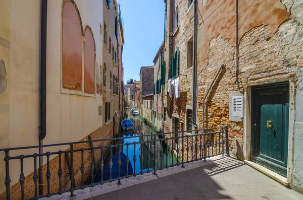 Narrow canal in Venice, Italy, with boats and historic houses, in a beautiful sunny day.