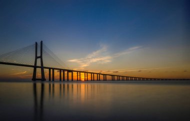 Portekiz, Lizbon 'daki Tagus Nehri boyunca uzanan Avrupa' nın en uzun köprüsü Vasco da Gama Köprüsü 'nde güzel bir gün doğumu..