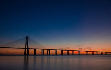 Portekiz, Lizbon 'daki Tagus Nehri boyunca uzanan Avrupa' nın en uzun köprüsü Vasco da Gama Köprüsü 'nde güzel bir gün doğumu..