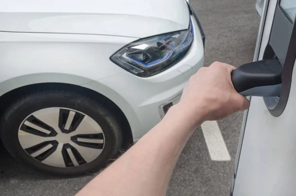 Man plugging in an electric car on the street station. New energy vehicles, environment friendly alternative energy for cars