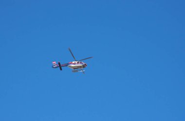 Avusturya federal polis helikopteri uçuyor, arkada mavi gökyüzü.