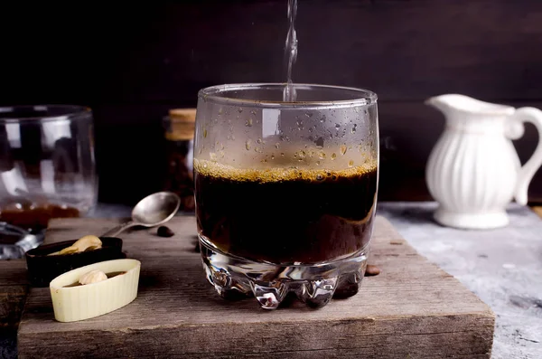 pouring boiling water into a glass of coffee chocolate candy and grains coffee latte preparation