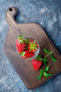 İştah açıcı olgun çilek rustik gri arka plan üzerinde cam. Uzay kopyalayın. üstten görünüm