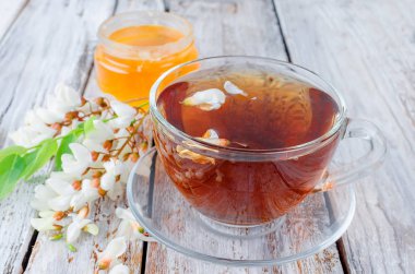 Çaydanlık ve şube akasya eski rustik ahşap masa üzerinde demlenmiş akasya çiçekleri bal ile şifa bitki çayı. 