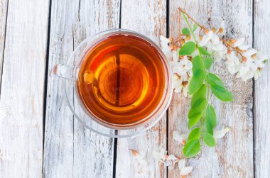 Çaydanlık ve şube akasya eski rustik ahşap masa üzerinde demlenmiş akasya çiçekleri bal ile şifa bitki çayı. 