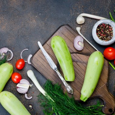 Genç bahar kabağı, domates, bitki ve baharatlar yukarıdan siyah arka planda. Kızartma için taze bahar sebzeleri. Bedava metin alanı olan arkaplan düzeni. Üst Manzara. Boşluğu kopyala.