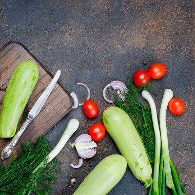 Genç bahar kabağı, domates, bitki ve baharatlar yukarıdan siyah arka planda. Kızartma için taze bahar sebzeleri. Bedava metin alanı olan arkaplan düzeni. Üst Manzara. Boşluğu kopyala.