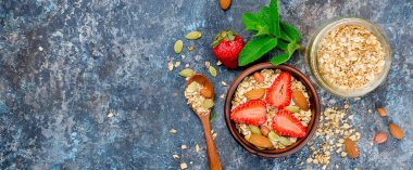 Taze gevrek, çilek, badem, fıstık ve tohum beyaz ahşap arka planda, seçici odak, bir seramik kase müsli fotoğraf tonda