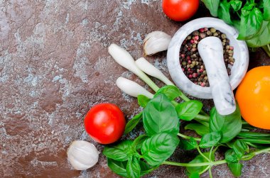 Olgun kırmızı ve sarı domates, yeşil soğan ve fesleğen, sarımsak, tuz ve baharat karanlık bir taş zemin üzerine. Üstten görünüm, kopya alanı. 