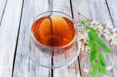 Çaydanlık ve şube akasya eski rustik ahşap masa üzerinde demlenmiş akasya çiçekleri bal ile şifa bitki çayı. 