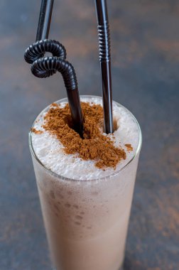 Sütlü çikolata kokteyl veya soğuk sütü ve buz ile çırpılmış kahve koyu arka plan üzerinde kopya alanı kakao serpin, 