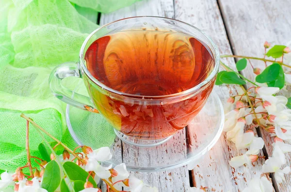 Çaydanlık ve şube akasya eski rustik ahşap masa üzerinde demlenmiş akasya çiçekleri bal ile şifa bitki çayı. 