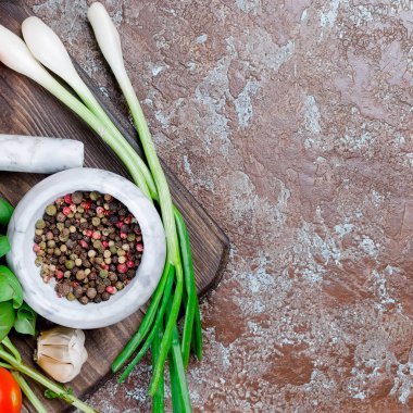 Olgun kırmızı ve sarı domates, yeşil soğan ve fesleğen, sarımsak, tuz ve baharat karanlık bir taş zemin üzerine. Üstten görünüm, kopya alanı. 