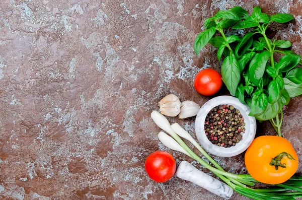 Olgun kırmızı ve sarı domates, yeşil soğan ve fesleğen, sarımsak, tuz ve baharat karanlık bir taş zemin üzerine. Üstten görünüm, kopya alanı. 