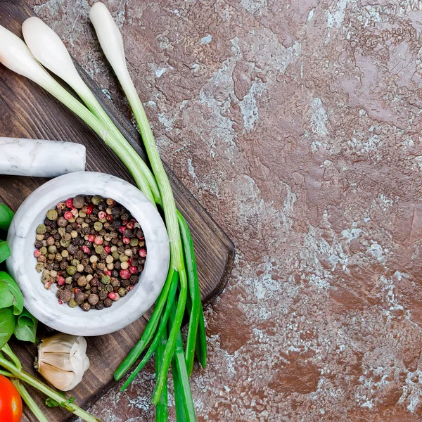 Olgun kırmızı ve sarı domates, yeşil soğan ve fesleğen, sarımsak, tuz ve baharat karanlık bir taş zemin üzerine. Üstten görünüm, kopya alanı. 