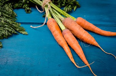 Bir grup eski mavi ahşap arka plan üzerinde yeşil yaprakları ile taze havuç. Sebze. Gıda. Uzay kopyalayın. üstten görünüm.