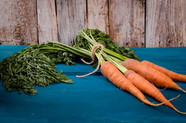 Bir grup eski mavi ahşap arka plan üzerinde yeşil yaprakları ile taze havuç. Sebze. Gıda. Uzay kopyalayın. üstten görünüm.