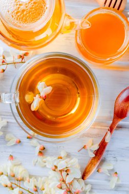 Çaydanlık ve şube akasya eski rustik beyaz ahşap masa üzerinde demlenmiş akasya çiçekleri bal ile şifa bitki çayı.