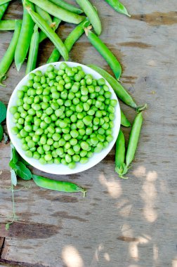 kase ve Pods bezelye üzerinde gri bir eski ahşap artalanları genç yeşil bezelye. Karanlık rustik tarzı.