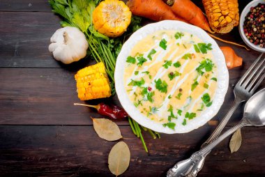 Ev yapımı Mısır krem çorbası ekşi krema, beyaz bir tabak ve dilim kızarmış Mısır koçanı karanlık eski rustik ahşap bir masa üzerinde otlar. üstten görünüm, kopya alanı