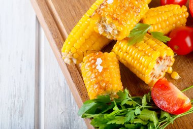 Lezzetli Barbecued Mısır koçanı otlar, sebzeler ve tuz bir tahta ve bir beyaz ahşap masa