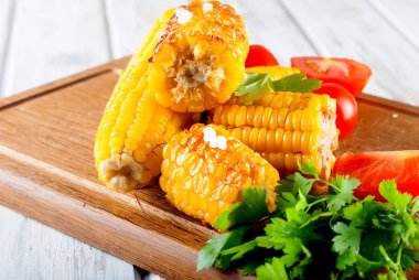Lezzetli Barbecued Mısır koçanı otlar, sebzeler ve tuz bir tahta ve bir beyaz ahşap masa