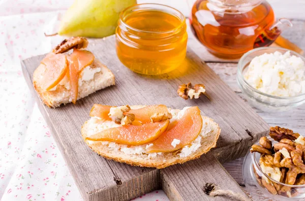 Breakfast set. tea with sandwiches with ricotta cheese and pear jam.   Cup of tea and glass teapot. Top view, copy space