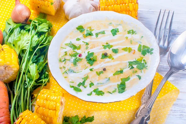 Ev yapımı Mısır krem çorbası ekşi krema, beyaz bir tabak ve dilim kızarmış Mısır koçanı Beyaz ahşap bir masa üzerinde otlar. üstten görünüm, kopya alanı 