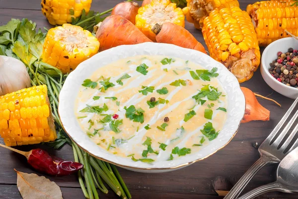 Ev yapımı Mısır krem çorbası ekşi krema, beyaz bir tabak ve dilim kızarmış Mısır koçanı karanlık eski rustik ahşap bir masa üzerinde otlar. üstten görünüm, kopya alanı