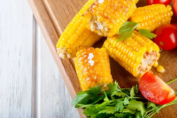 Lezzetli Barbecued Mısır koçanı otlar, sebzeler ve tuz bir tahta ve bir beyaz ahşap masa