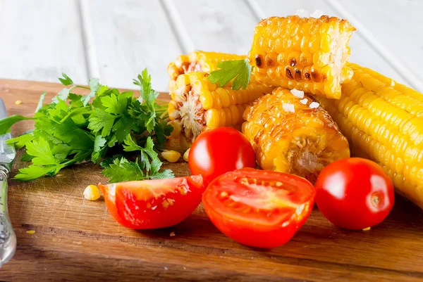 Lezzetli Barbecued Mısır koçanı otlar, sebzeler ve tuz bir tahta ve bir beyaz ahşap masa